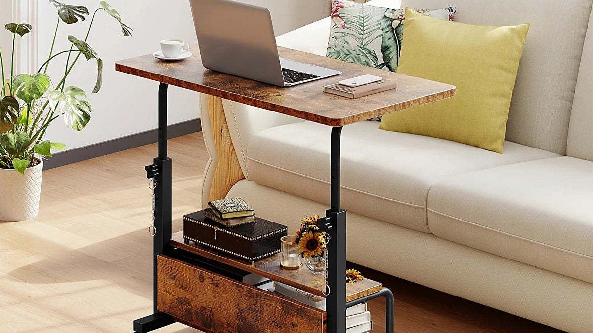 Mobile height-adjustable sit-stand desk on casters beside a sofa in a bright living room