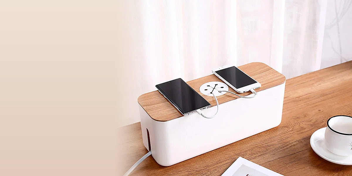 White cable management box with a wooden lid charging two phones on a walnut desk
